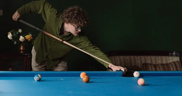 A guy playing snooker