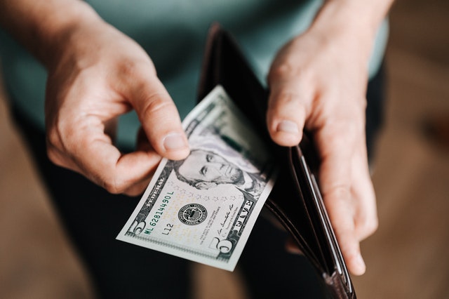 Man putting a dollar note in wallet