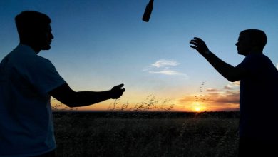 two men throwing a beer bottle