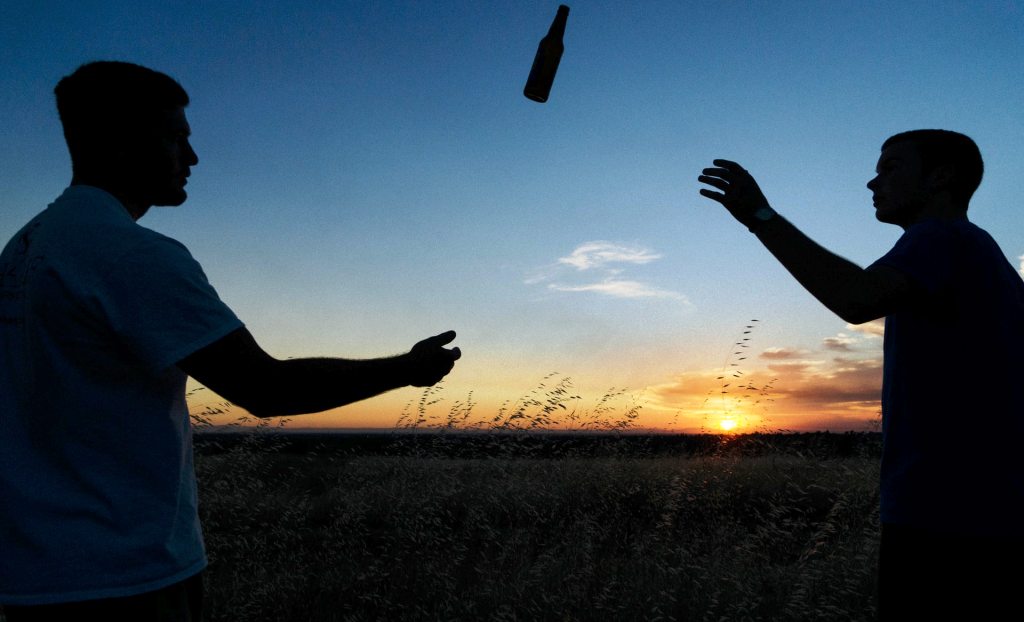 two men throwing a beer bottle