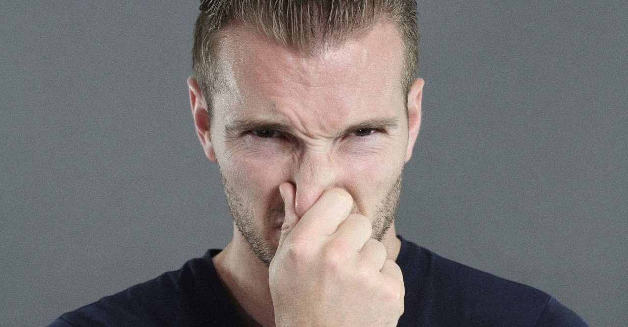 A man stopping his nose from smelling bad house smells