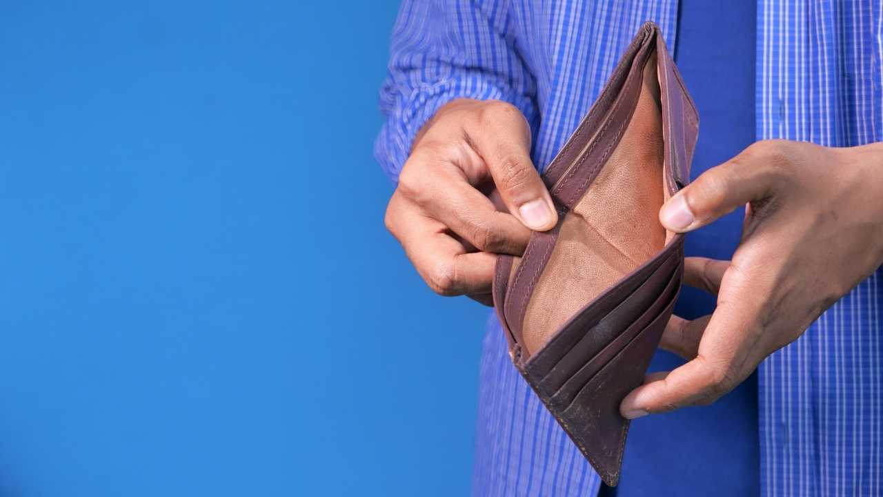 A man in debt showing empty purse