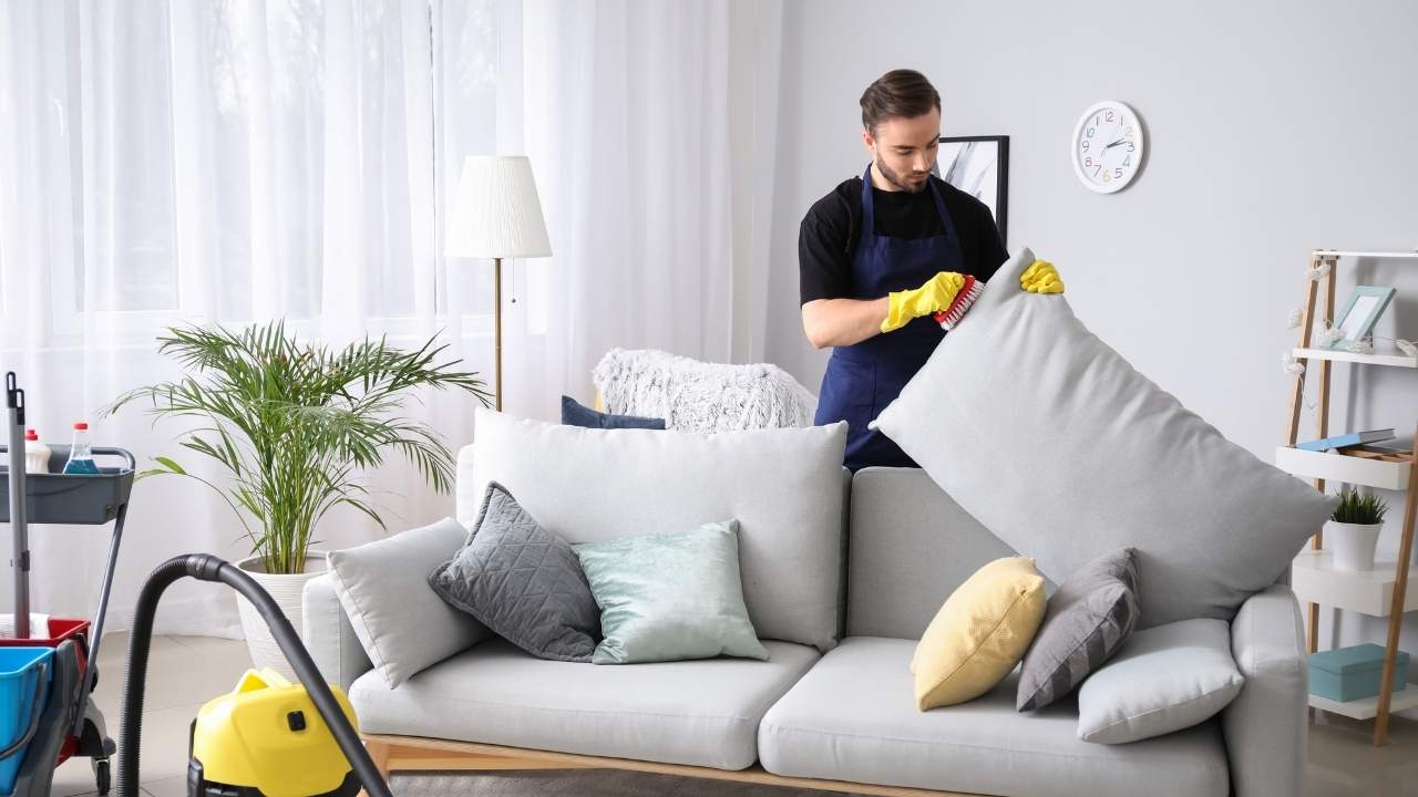 Man cleaning sofa pillows