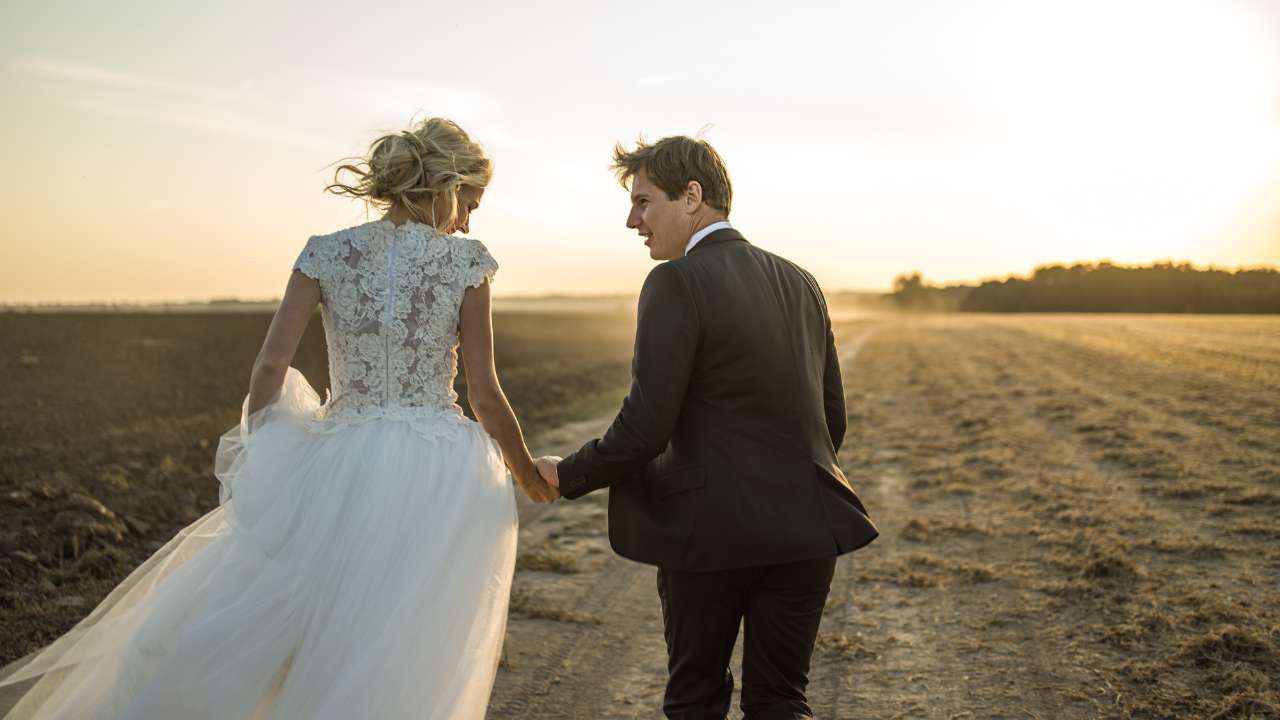  A newlywed couple posing with their cherished wedding keepsakes, highlighting the bride's gorgeous dress