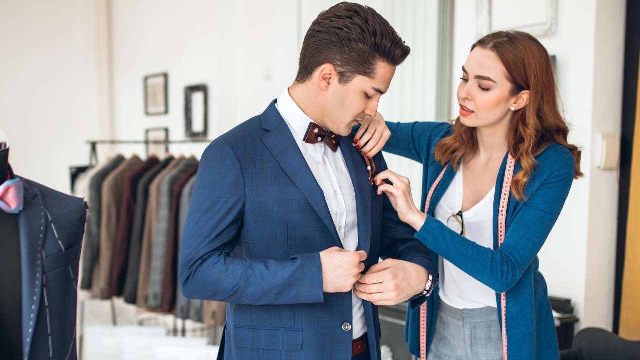 female tailor helping a man wearing Bowtie with a suit