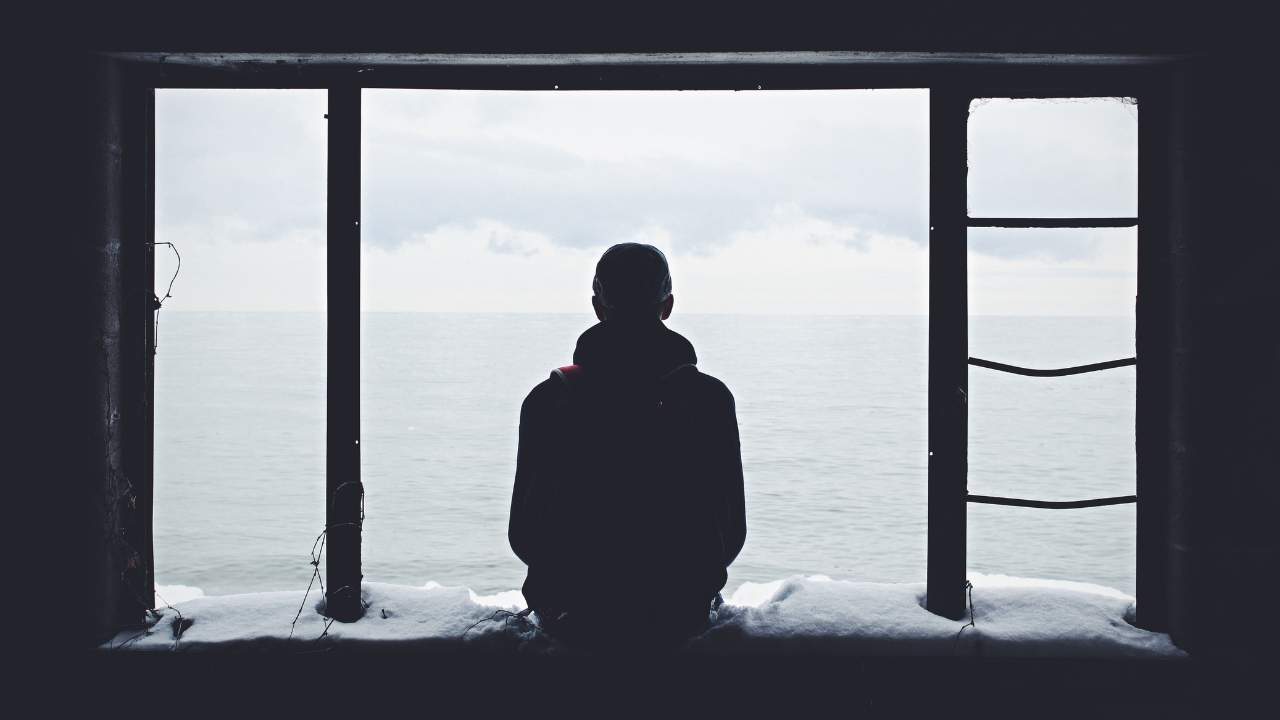 male sitting alone by a window