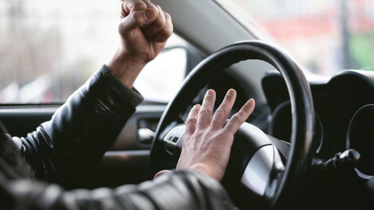 man honking horn in car