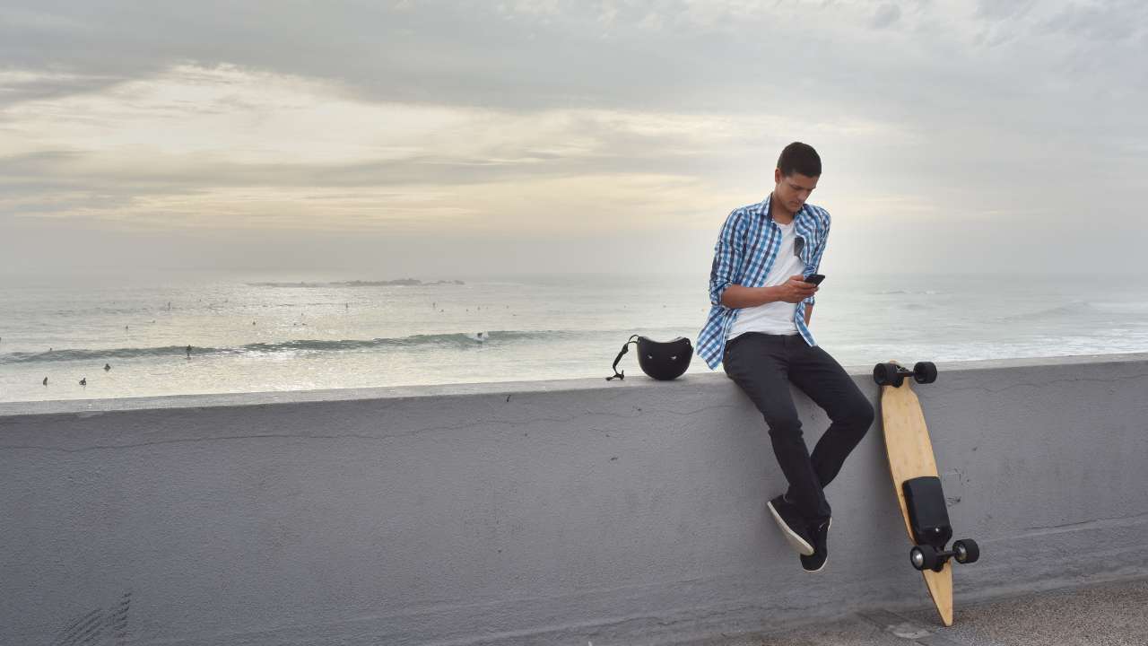 a  guy sitting near Electric Skateboard