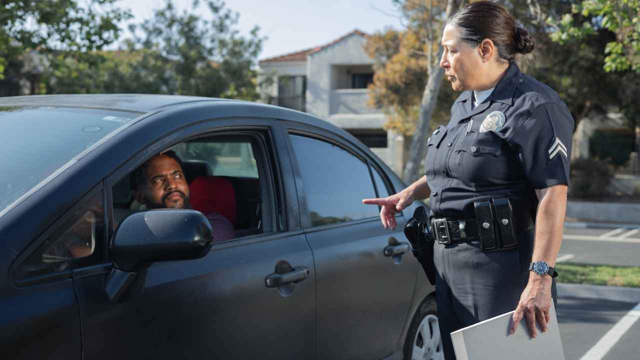 police offer standing beside a guy in car