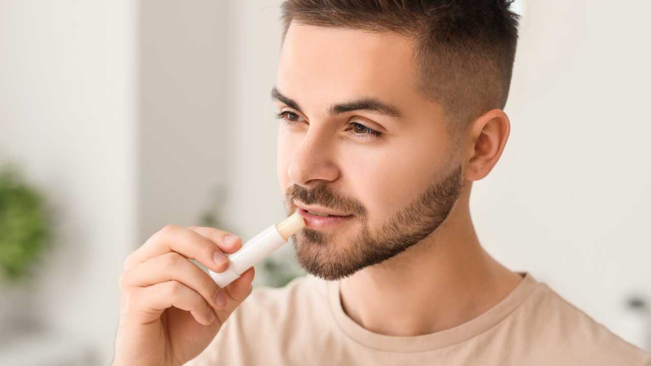 man using lip balm on his lips